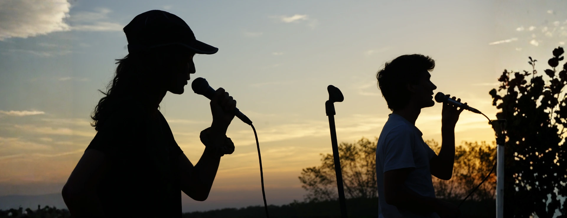 Blaise et Nico chantant sur scène au coucher du soleil lors d'un concert